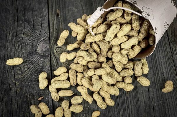Amendoins soltos na casca em uma superfície de madeira cinza, tonelada vintage — Fotografia de Stock
