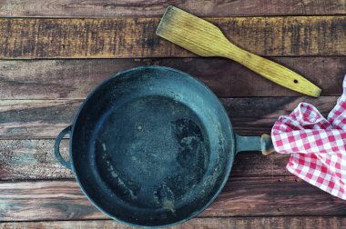 Kahverengi ahşap bir yüzeye kocaman boş bir demir tava.