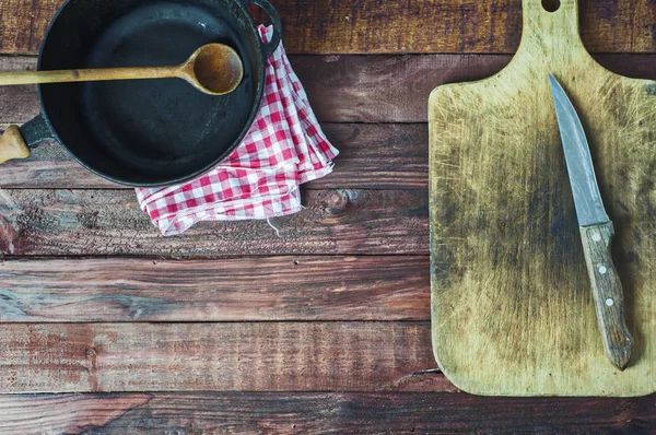 Black cast iron pan and cutting board on brown wooden surface — Stock Photo, Image