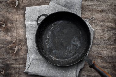 Empty black cast-iron frying pan on a textile napkin clipart
