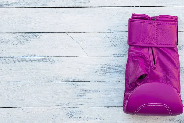 Uma luva de boxe rosa em uma superfície de madeira branca — Fotografia de Stock