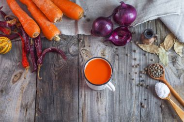 Taze havuç suyu bir demir kupa gri bir ahşap yüzeye 