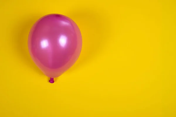 Globo inflado de aire rosa en la superficie amarilla — Foto de Stock