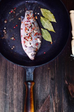Baharat siyah bir dökme demir tava üzerinde balık sazan 