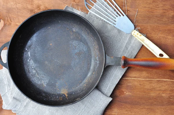 Esvaziar frigideira de ferro fundido preto e espátula de ferro na mesa — Fotografia de Stock