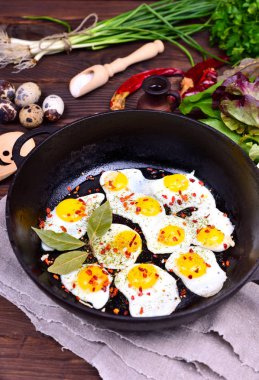 Siyah dökme demir tavada kızarmış bıldırcın yumurtası ile 