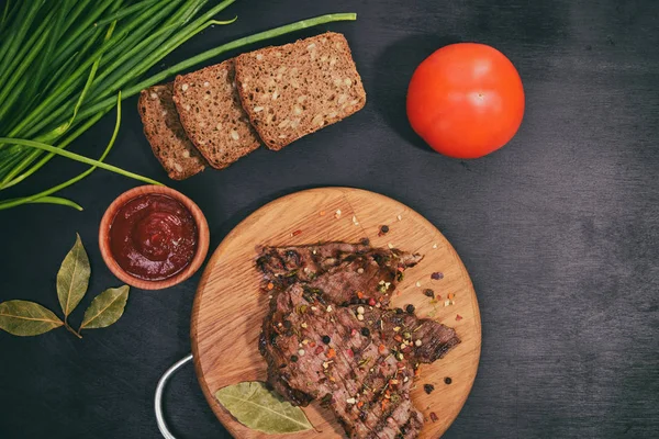 Carne a la parrilla en un tablero de madera con verduras frescas — Foto de Stock