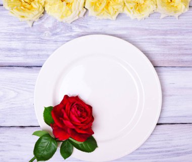 Kırmızı bir gül ile boş beyaz plaka 