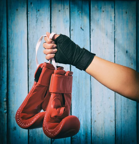 La mano femenina sostiene un par de guantes rojos de kickboxing —  Fotos de Stock