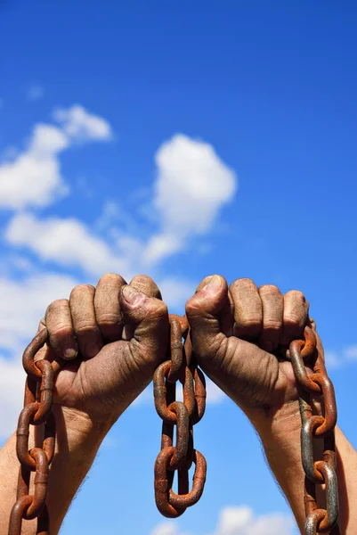 Dos manos de hombre en el barro sostienen una cadena metálica oxidada —  Fotos de Stock