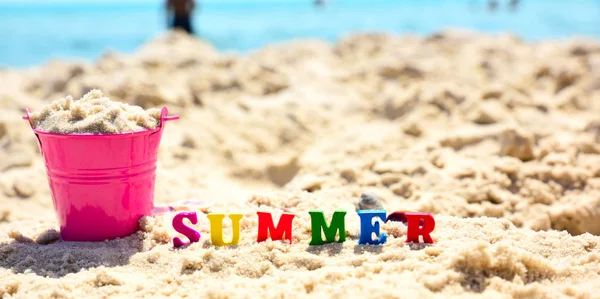 Letras de madera multicolor en la palabra verano en la arena —  Fotos de Stock