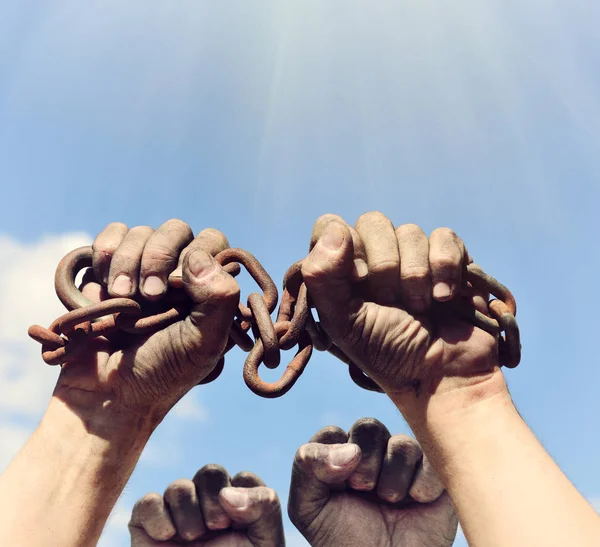 dirty male hands wrapped in a rusty iron chain