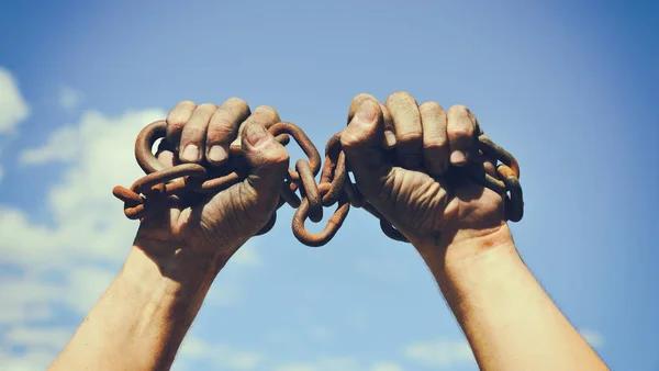 Two dirty male hands wrapped in a rusty iron chain — Stock Photo, Image