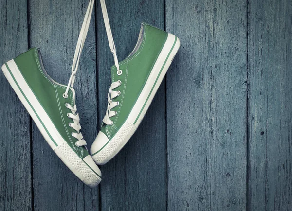 Green youth sneakers hanging on a nail — Stock Photo, Image