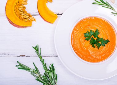 bir yuvarlak beyaz tabak içinde kremalı balkabağı çorbası 