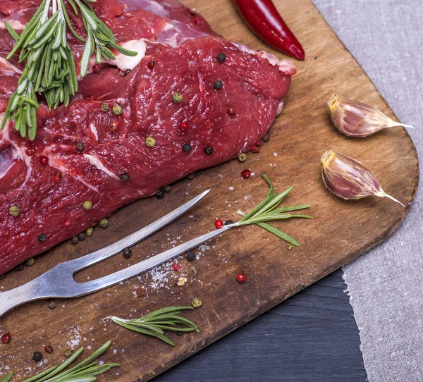 Rauw rundvlees op een bruin houten bord — Stockfoto