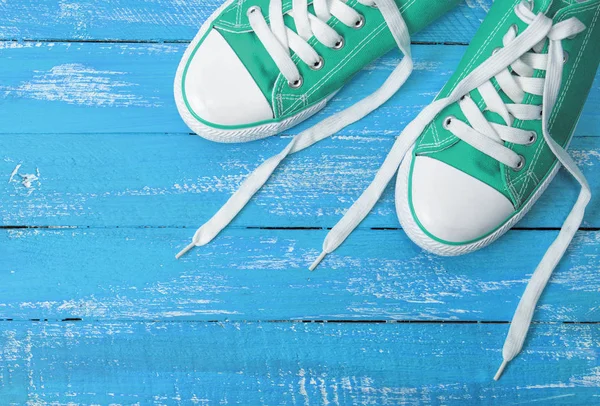 Зелені текстильні кросівки на синьому дерев'яному фоні — стокове фото