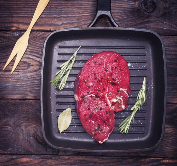 Filete de carne cruda en una sartén de cuarteto negro — Foto de Stock