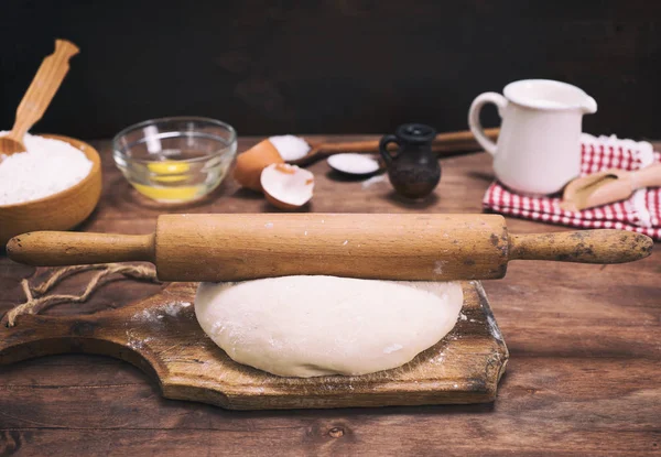 dough from white flour and a wooden rolling pin