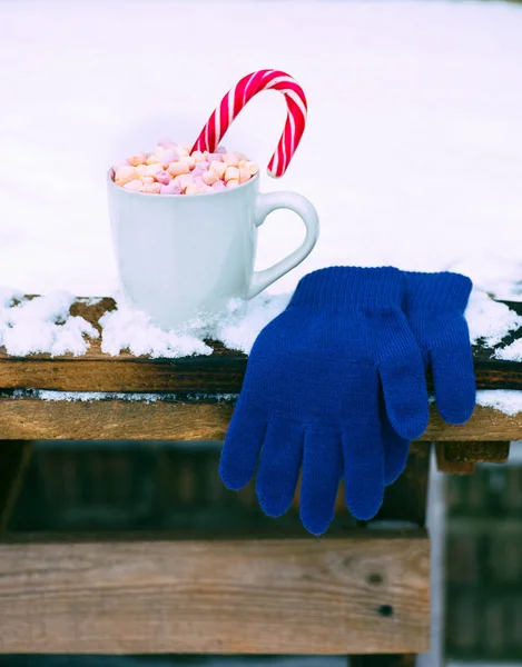 Cup with hot chocolate and marshmallow on a snow-covered table — Stock Photo, Image