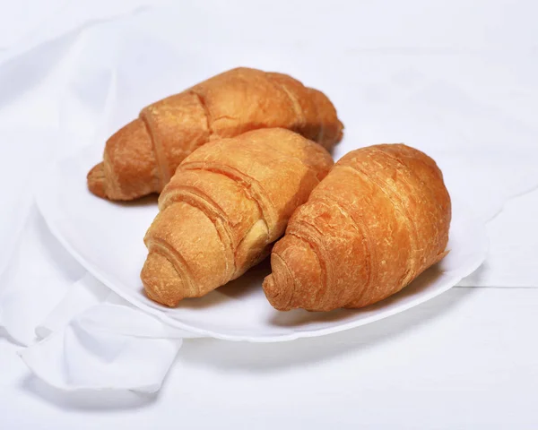 Three freshly baked croissants on a white ceramic plate — Stock Photo, Image