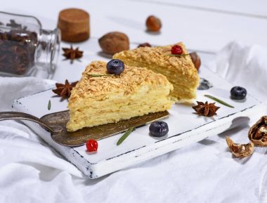 Beyaz ahşap tahta üzerinde krem ile iki pişmiş kek Napoleon