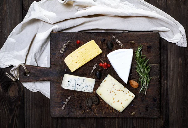 茶色の木の板にさまざまなチーズの部分 — ストック写真