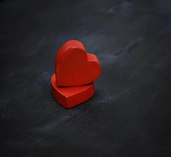 Dos corazones rojos de madera sobre un fondo negro —  Fotos de Stock