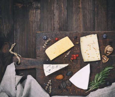 bir kahverengi ahşap tahta üzerinde farklı peynir parçalarını: brie, roque