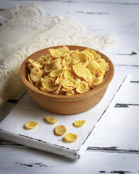 Cornflakes in a wooden bowl on a white board — Stock Photo, Image