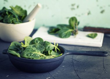 bir siyah yuvarlak dökme demir tavada yeşil ıspanak yaprakları 