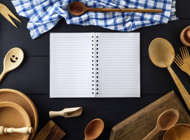siyah ahşap bir masa üstten görünüm Ahşap mutfak öğeleri ortasında bir yay üzerinde beyaz çarşaf bir çizgi ile boş kağıt Not defterini açın