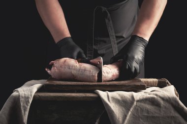 Siyah lateks giymiş şef parça parça kesilmiş çiğ tavşan eti.