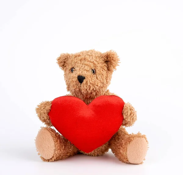 Cute brown teddy bear holding a big red heart on a white backgro Royalty Free Stock Images