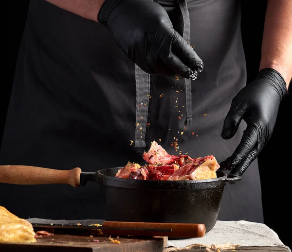 Chef de uniforme preto e luvas de látex tempero mea de frango cru — Fotografia de Stock