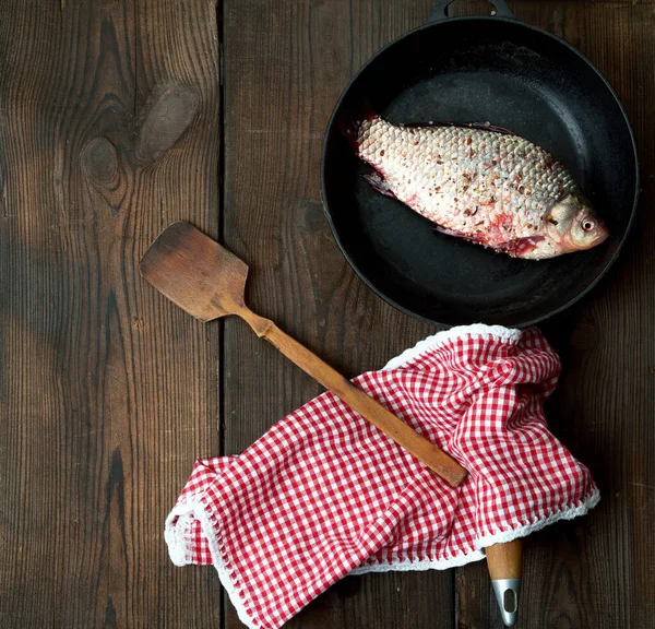 fresh crucian fish sprinkled with spices and lies in a black rou