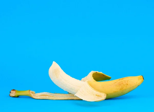 Peeled ripe yellow banana on a blue background — Stock Photo, Image
