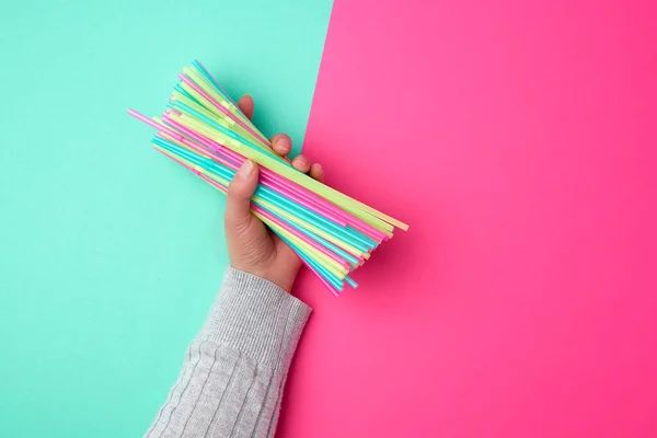 Mano femenina sosteniendo tubos de cóctel de plástico multicolor —  Fotos de Stock