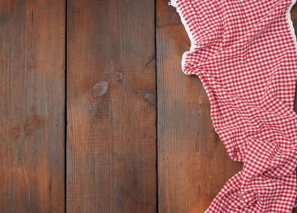 Toalla de cocina a cuadros rojo blanco sobre un fondo de madera marrón — Foto de Stock