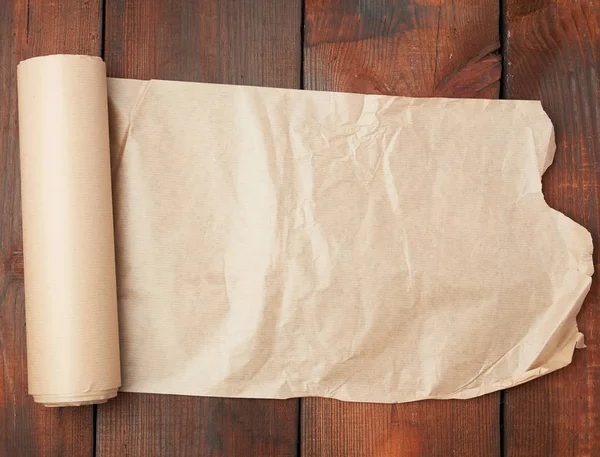 Role nekrouceného hnědého papíru na dřevěném povrchu ze staré desky — Stock fotografie
