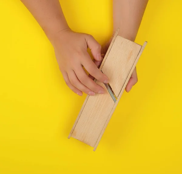 Rallador de madera para verduras en las manos sobre un fondo amarillo — Foto de Stock