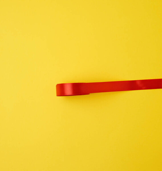 red silk ribbon on a yellow background, festive backdrop