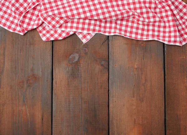 Toalla de cocina a cuadros rojo blanco sobre un fondo de madera marrón — Foto de Stock