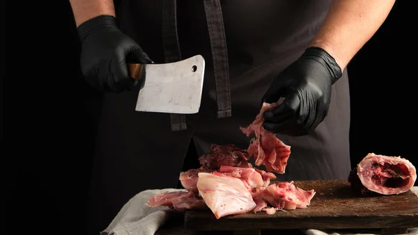 Chef em luvas de látex preto segura uma faca grande e corta em pedaços — Fotografia de Stock