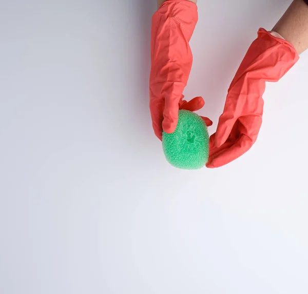 Mão em uma luva de laranja mantém uma esponja de cozinha — Fotografia de Stock