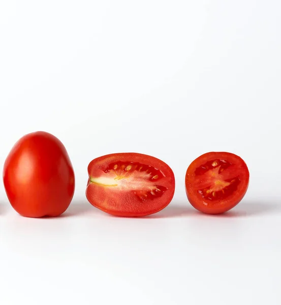 Tomates enteros rojos maduros y trozos sobre un fondo blanco, otoño — Foto de Stock