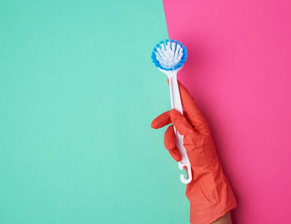Weiße Reinigungsbürste aus Kunststoff in der Hand, orangefarbener Schutzhandschuh an — Stockfoto
