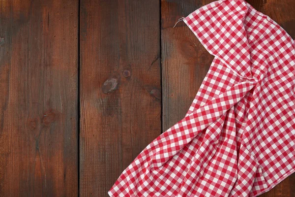 Біло-червоний картатий кухонний рушник на коричневому дерев'яному фоні — стокове фото