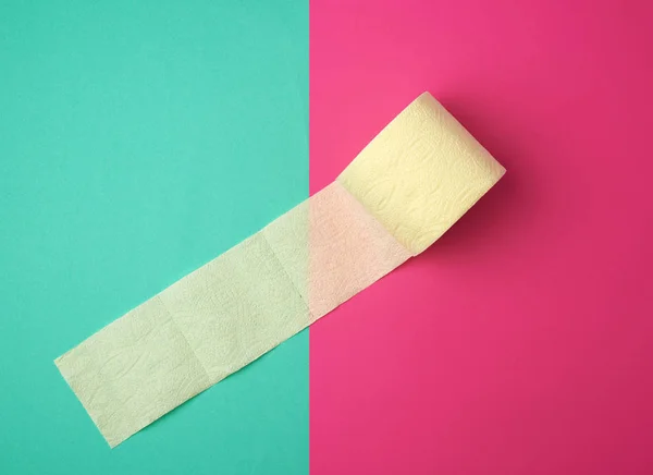 Miękki żółty papier toaletowy w rolce na zielono-różowym tle — Zdjęcie stockowe