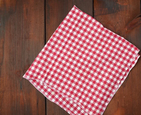 Toalla de cocina a cuadros rojo blanco sobre un fondo de madera marrón —  Fotos de Stock